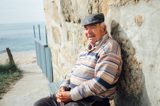 a man sitting on a bench next to a stone wall