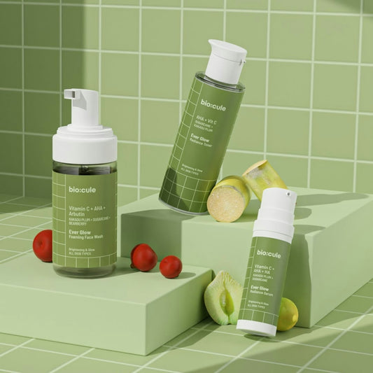 Skincare bottles with fruit and sugarcane on green blocks.